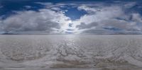 the vast white desert is full of large clouds as it passes by in time lapse