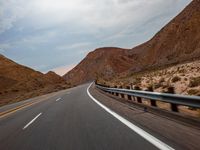 a car is driving through a valley in the desert, with a mountain range behind it