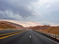 highway with yellow line and mountains in background in dusk time, during daytime, near desert