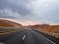 highway with yellow line and mountains in background in dusk time, during daytime, near desert