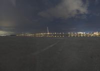 view of a harbor from the runway at night with clouds in sky and a train in the distance