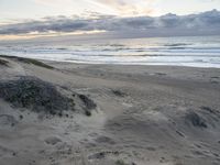 an empty beach with footprints in the sand next to the water and waves coming into the beach