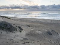 an empty beach with footprints in the sand next to the water and waves coming into the beach