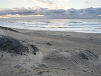 an empty beach with footprints in the sand next to the water and waves coming into the beach