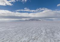 the snow covered desert looks deserted and barren at the bottom of it, with mountains in the distance