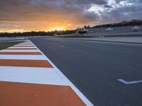 the sun sets in on an airport runway with a cloudy sky above it and some orange stripes