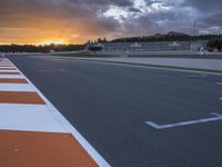 the sun sets in on an airport runway with a cloudy sky above it and some orange stripes