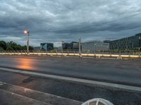 a dark sky over an empty street and street lamps, with the lights turned on and dark clouds are rolling across the distance