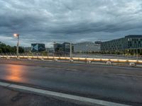 a dark sky over an empty street and street lamps, with the lights turned on and dark clouds are rolling across the distance