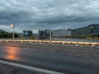 a dark sky over an empty street and street lamps, with the lights turned on and dark clouds are rolling across the distance