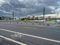 a bike path near a road in front of a big building with many windows on it