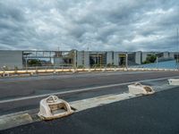 an abandoned parking lot sits on a road under an overcast sky with grey clouds