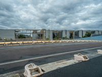 an abandoned parking lot sits on a road under an overcast sky with grey clouds