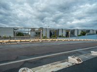 an abandoned parking lot sits on a road under an overcast sky with grey clouds