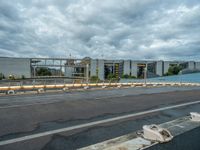 an abandoned parking lot sits on a road under an overcast sky with grey clouds