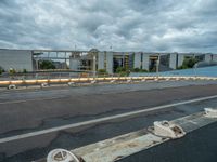 an abandoned parking lot sits on a road under an overcast sky with grey clouds