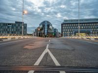 a large long, empty street with multiple buildings and lights on top of it with cloudy skies