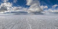 the sky above a large, flat landscape with snow on it, clouds and a sky background