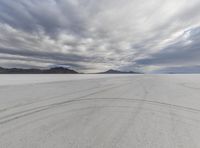 the view of a very wide empty desert with tracks in it and clouds overhead for an artistic look