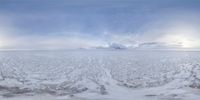 a large field with lots of snow and clouds in it under a blue sky above the horizon