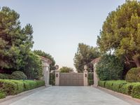 the driveway entrance leads to a gate and outdoor privacy paneled doors, which are lined with greenery