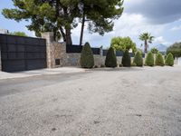 driveway with cars parked on it with trees and bushes on either side, with stone pillars