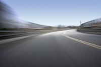 a fast moving shot of a car driving across a bridge over water and bridge above it