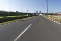 the car is driving down the road beside a tunnel with street signs above it on a sunny day