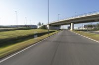 the car is driving down the road beside a tunnel with street signs above it on a sunny day