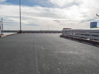the car is driving on a road near some railings and poles with an overhang