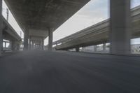 a view looking at the underside of an overpass, driving through a city street