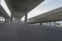 a view looking at the underside of an overpass, driving through a city street