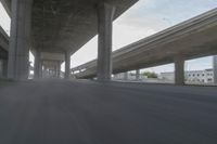 a view looking at the underside of an overpass, driving through a city street