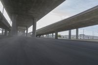 a view looking at the underside of an overpass, driving through a city street