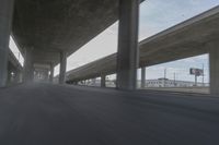 a view looking at the underside of an overpass, driving through a city street