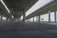 a view looking at the underside of an overpass, driving through a city street