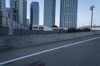 a car is driving past tall skyscrapers on the freeway outside a city center building