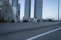 a car is driving past tall skyscrapers on the freeway outside a city center building