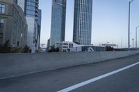 a car is driving past tall skyscrapers on the freeway outside a city center building