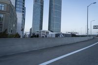 a car is driving past tall skyscrapers on the freeway outside a city center building