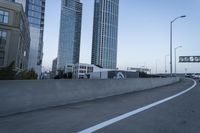 a car is driving past tall skyscrapers on the freeway outside a city center building