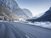 a car drives down a mountain road in the alpss next to the town of greifgene