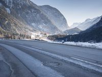 a car drives down a mountain road in the alpss next to the town of greifgene