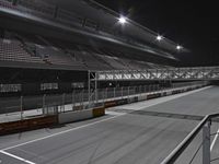 a race track with multiple lights on a dark night sky and white stripes running through the ground