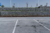 a paved parking lot near brick walls and a stone wall fence surrounding it with a pole