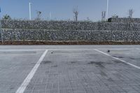 a paved parking lot near brick walls and a stone wall fence surrounding it with a pole