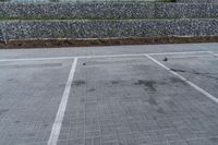 a paved parking lot near brick walls and a stone wall fence surrounding it with a pole
