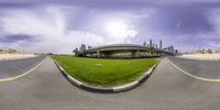 there is a fisheye photo of a grass covered field and a view of buildings