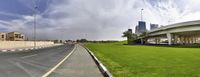 a green lawn and some tall buildings on the side of a road that is not as grassy