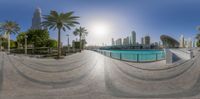 a 360 - view photo of the city skyline showing a circular fountain and palm trees